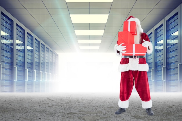 Santa llevando regalos contra el pasillo del servidor en un entorno desértico