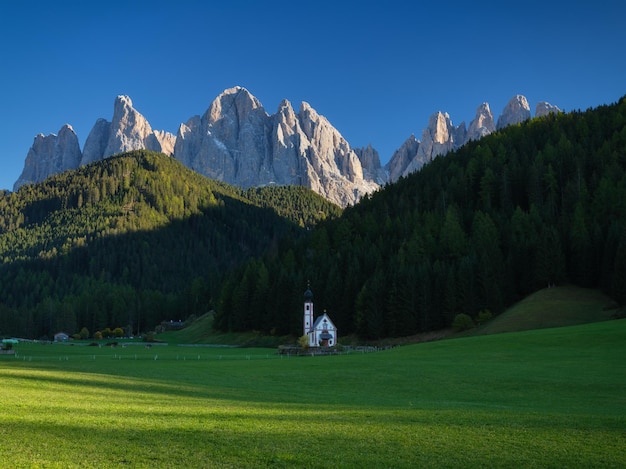 Santa Maddalena Val di Funes Dolomite Alpes Itália Igreja no prado As montanhas e a floresta antes do pôr do sol Paisagem natural no verão Foto em alta resoluçãoxA