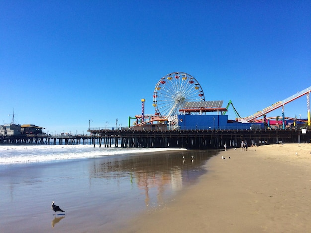 Foto santa monica pier am strand gegen den klaren blauen himmel