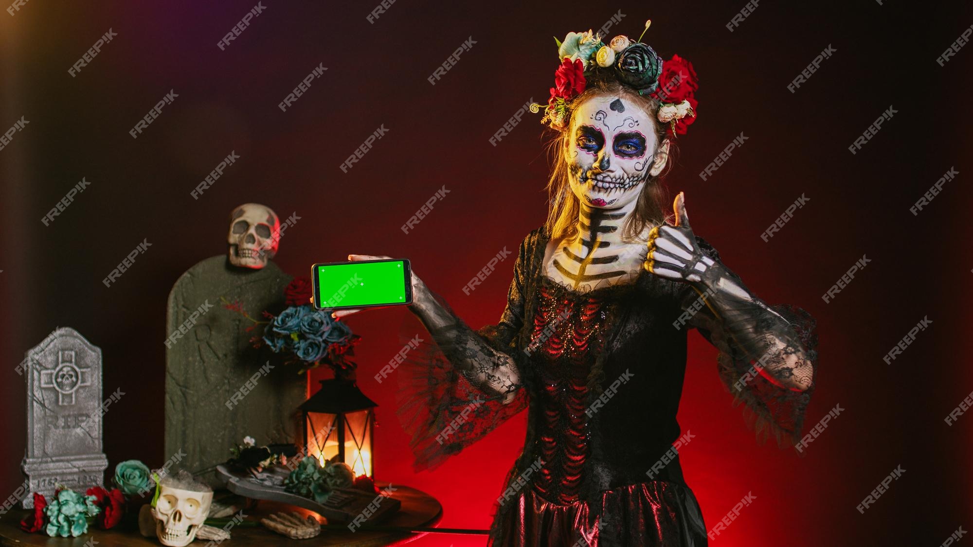 Santa muerte sosteniendo un teléfono móvil con una pantalla verde en el  estudio, mostrando una plantilla de espacio de copia en blanco. mujer  vestida como diosa sagrada con maqueta de clave de