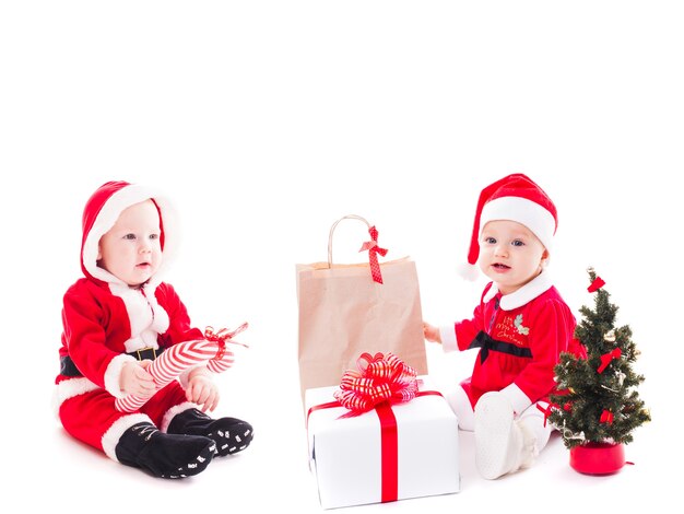 Santa niña y niño con caja de regalo y adornos navideños en blanco