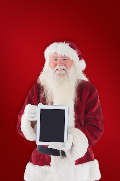 Santa presenta un tablet PC contra el fondo rojo.