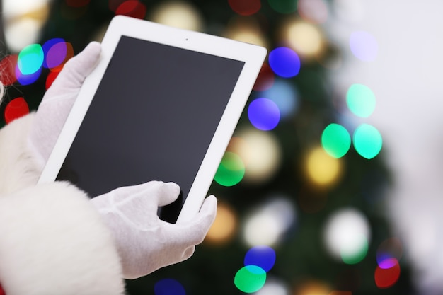 Santa sosteniendo la tableta en el árbol de Navidad