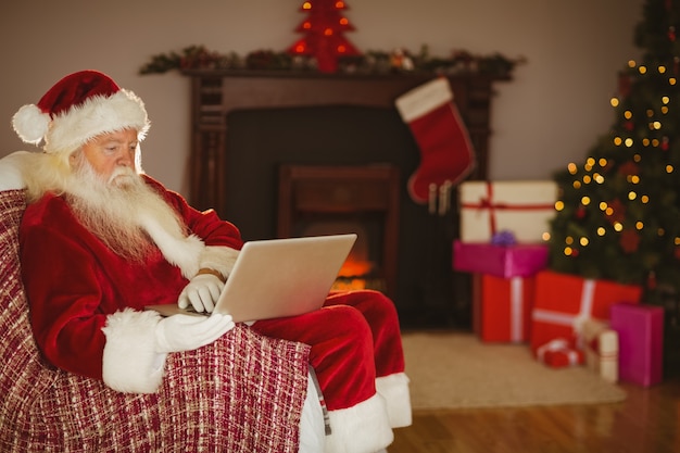 Santa usando o laptop no sofá no Natal