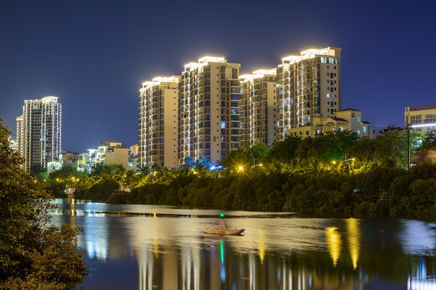 Sanya, Hainan, China - 25 de enero de 2020: Vista nocturna de la ciudad de Sanya con edificios, estructuras, carreteras, aceras, postes, puentes de iluminación multicolor brillante.