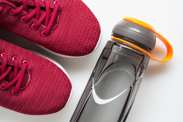 Sapatas vermelhas do esporte e garrafa da água. fundo de estilo de vida ativo e saudável.