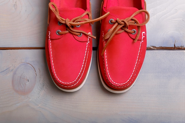 Sapatos de barco vermelho sobre fundo de madeira. vista do topo.