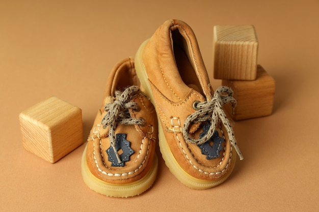 Sapatos de bebê e cubos de madeira em fundo bege.