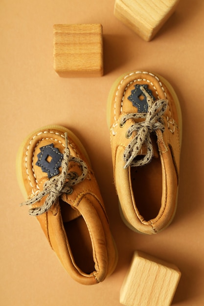 Sapatos de bebê e cubos de madeira em fundo bege.