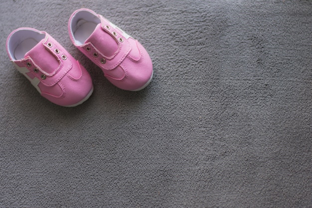 Foto sapatos de bebê rosa colocados sobre um fundo cinza