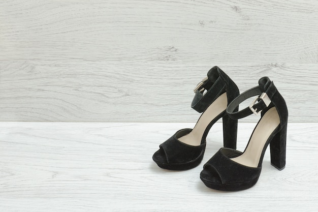 Sapatos de camurça preta em um fundo de madeira. Conceito elegante