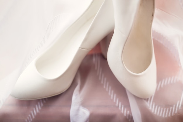 Sapatos de casamento de mulheres brancas lindas em pé em um tule