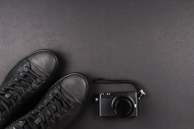 Sapatos de couro pretos masculinos e uma câmera preta em um fundo preto Copiar espaço