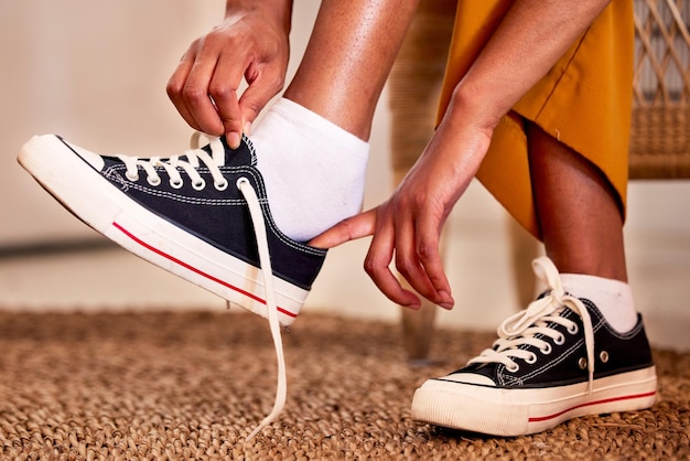 Sapatos de mãos e rendas se preparando para uma viagem a pé ou compras no chão do carpete ou tapete em casa Mão da pessoa amarrando cadarços ajustando ou calçando o sapato em preparação para uma viagem ou viagem a pé