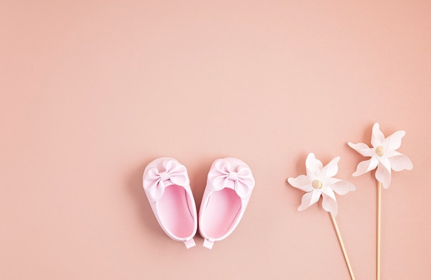 Sapatos de menina bonito bebê recém-nascido com decoração festiva sobre parede rosa.