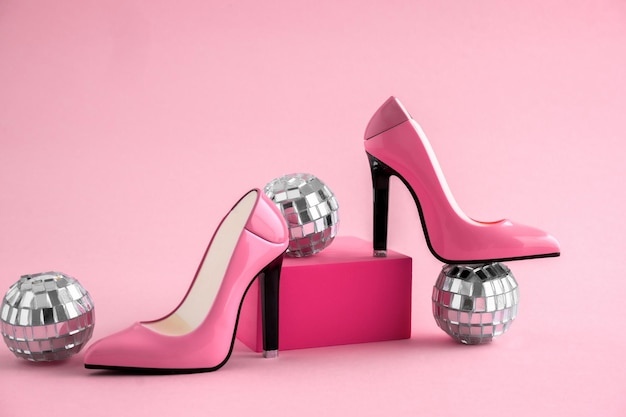 Foto sapatos de salto alto com bolas de discoteca em fundo rosa
