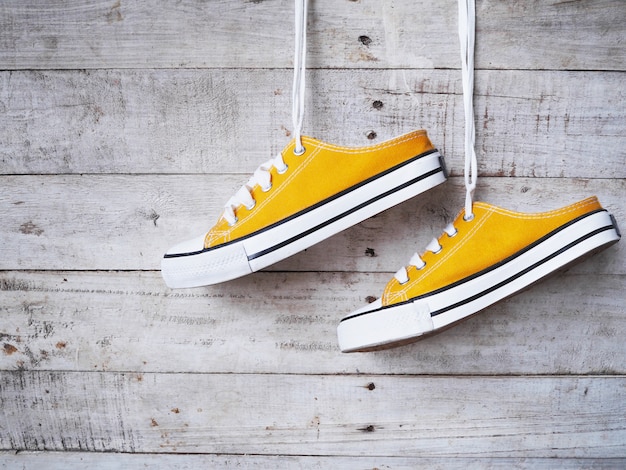 Sapatos de tênis amarelo com cadarço branco pendurado