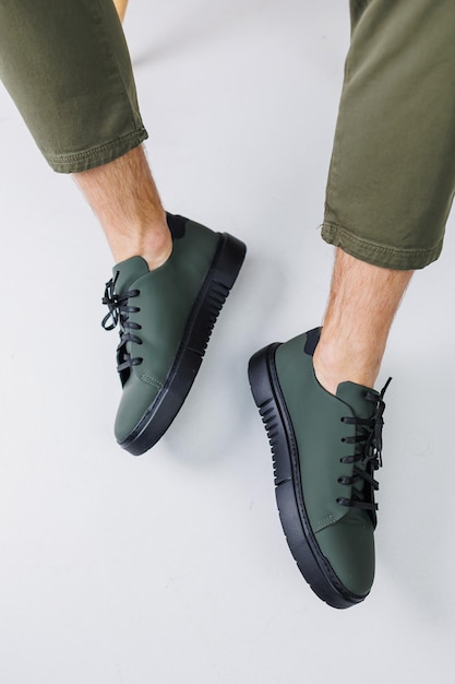 Sapatos de verão Closeup de pernas masculinas em calças verdes e tênis casuais verdes Sapatos masculinos de couro de verão
