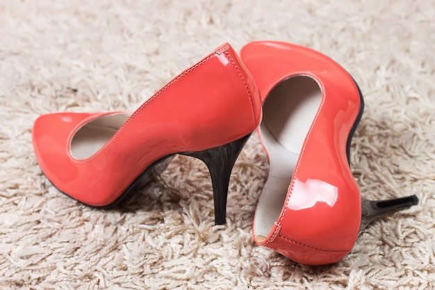 Sapatos femininos de salto alto vermelho em um tapete no chão