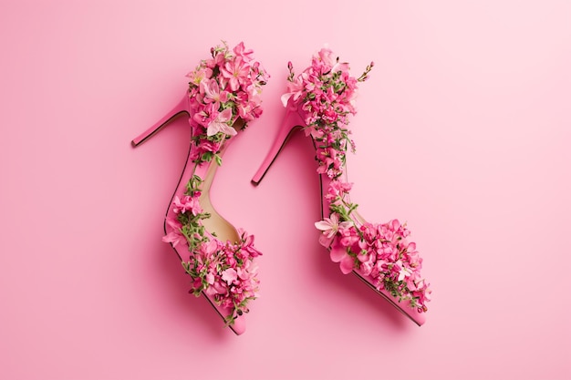 Sapatos femininos feitos de flores em fundo rosa com espaço de cópia Sapatos de salto alto decorados com flores em flor Moda e conceito de venda de primavera minimal criativo calçado de verão para mulher