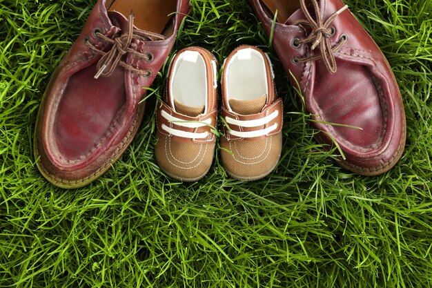 Sapatos grandes e pequenos em fundo de grama verde