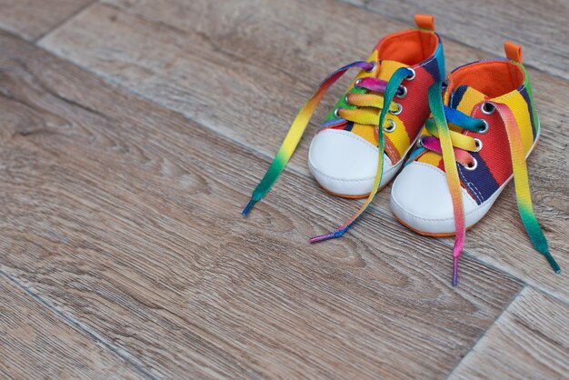 Sapatos infantis coloridos no chão de madeira