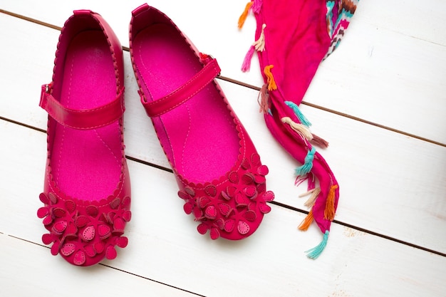 Sapatos infantis rosa brilhante em um fundo de madeira