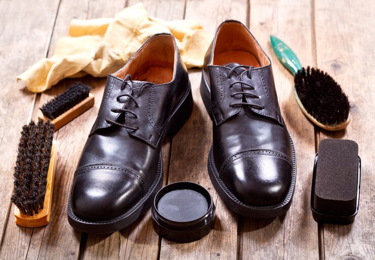 Foto sapatos masculinos negros com acessórios de tratamento em um fundo de madeira