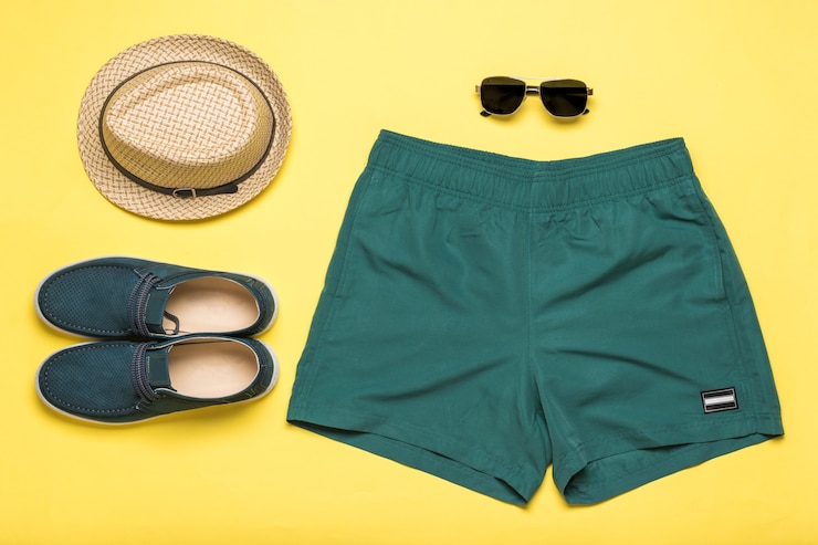 Foto sapatos masculinos, shorts, chapéu e óculos em um fundo amarelo. acessórios masculinos populares de verão.