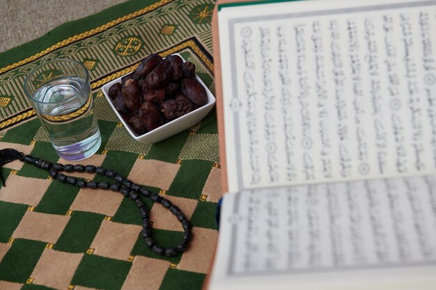 Sarajevo, Bósnia e Herzegovina - 28 de maio de 2019 Iftar, datas secas, copo de água do Alcorão Sagrado e tasbih no tapete de oração ou sejadah no conceito de educação islâmica do Ramadã