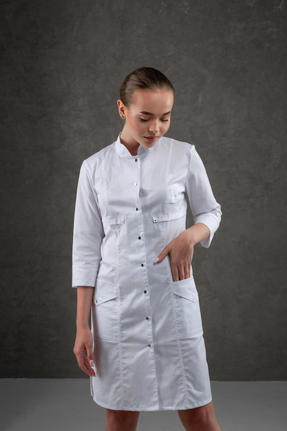 Saratov Russia 7202022 Ropa médica blanca en el modelo de niña Concepto de vestimenta para médico y enfermera sobre un fondo neutro gris oscuro