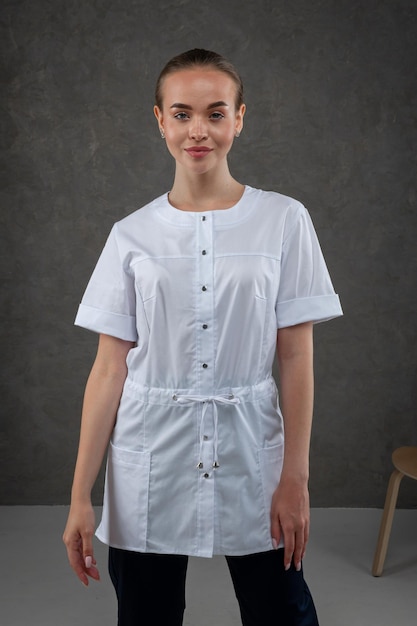 Saratov Russia 7202022 Ropa médica blanca en el modelo de niña Concepto de vestimenta para médico y enfermera sobre un fondo neutro gris oscuro