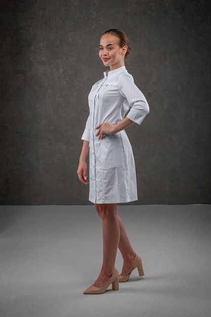 Saratov Rússia 7202022 Roupas médicas brancas no modelo de menina Conceito de vestido para médico e enfermeiro em um fundo neutro cinza escuro