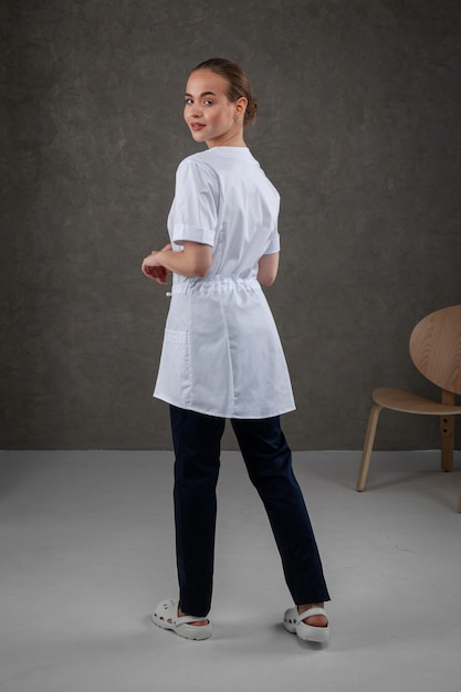 Saratov Russland 7202022 Medizinische Kleidung weiß auf dem Mädchenmodell Kleidkonzept für Arzt und Krankenschwester auf einem dunkelgrauen neutralen Hintergrund