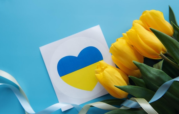 Sarde mit Herz in den Farben der ukrainischen Flagge und gelben Tulpen auf blauem Grund Unterstützung für die Ukraine