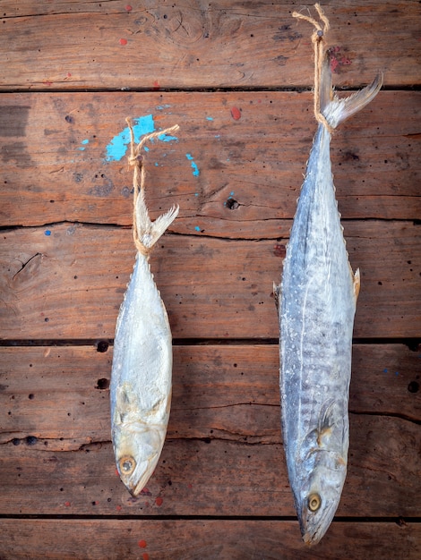 Sardina y barracuda saladas colgando sobre fondo de madera vieja