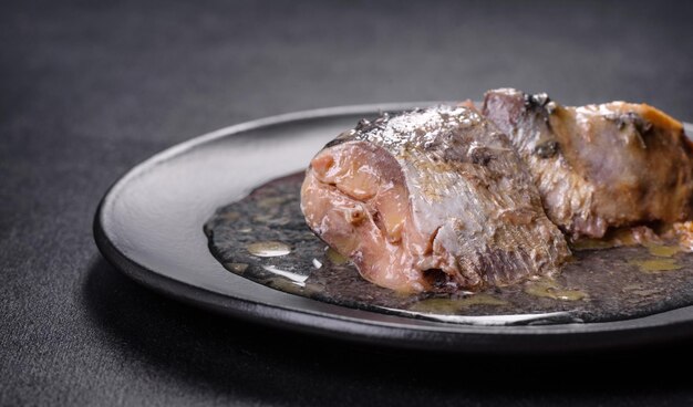 Sardina enlatada en aceite sobre un plato redondo negro sobre un fondo de hormigón oscuro Haciendo un delicioso tentempié