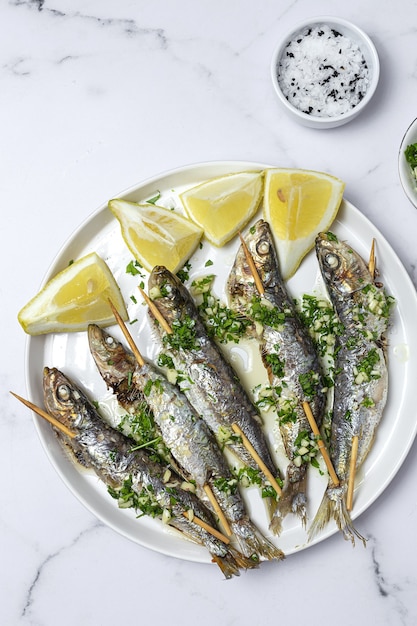 Sardinas caseras a la parrilla con ajo, aceite de oliva, perejil fresco y limón.Concepto de comida saludable