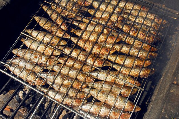 Sardinas a la parrilla en una parrilla de metal mientras se parrilla en un fuego