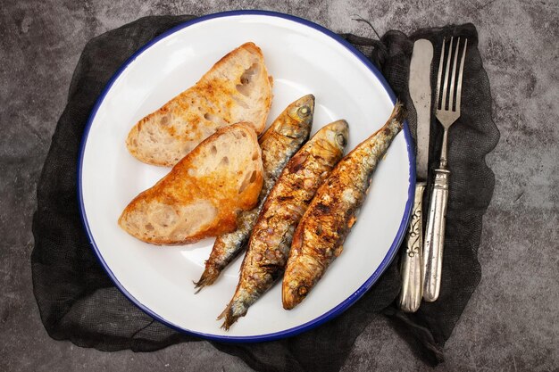 Sardinas a la parrilla con salsa en pan fresco en un plato blanco