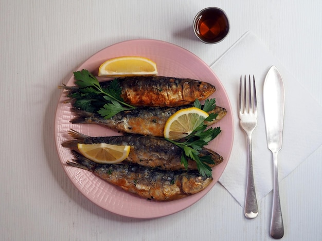 Sardinha frita com limão e ervas num prato