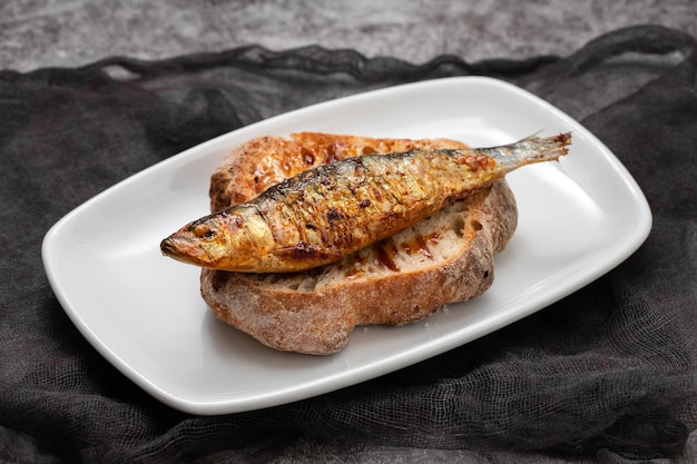 Sardinhas grelhadas com molho de pão fresco em prato branco