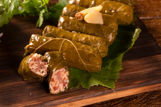 Sarma - Arroz y menta envuelto en hojas de parra sobre fondo de madera.