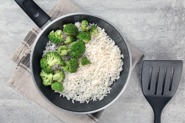 Sartén con arroz y brócoli en la mesa