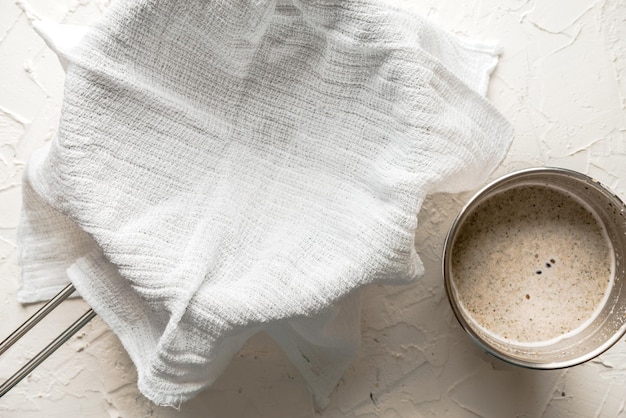 La sartén está cubierta con una servilleta y leche de cáñamo en una mesa blanca horizontal