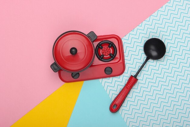 Foto sartén de juguete en la estufa y cucharón de sopa. tendencia de color pastel. vista superior