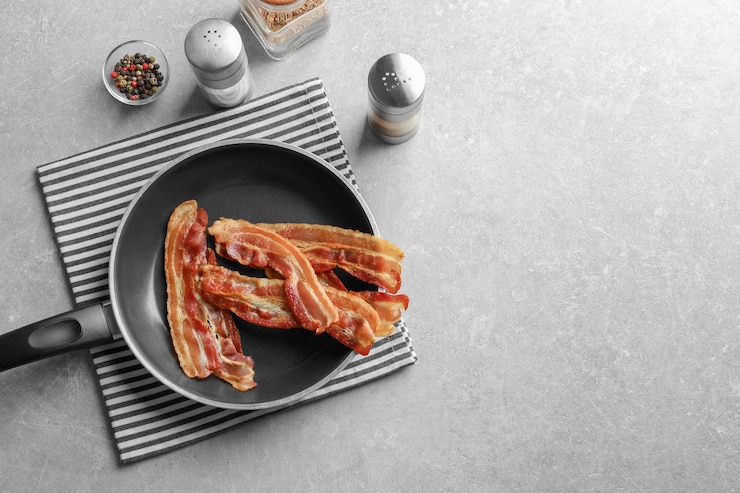 Foto sartén con rashers de tocino cocidos en la mesa