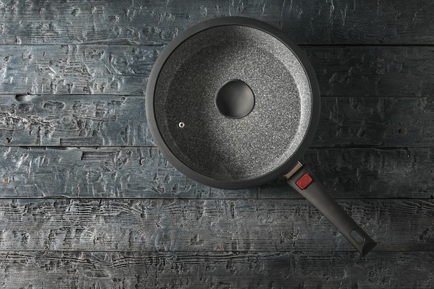 Una sartén con tapa de vidrio sobre una mesa de madera negra La vista desde arriba