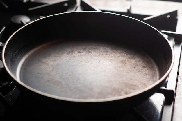 Sartén vacía en la estufa Una vieja sartén se calienta en una cocina casera