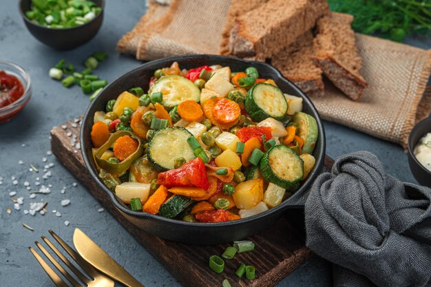 Sartén con verduras al horno sobre un fondo azul grisáceo. Un plato vegetariano saludable. Vista lateral, primer plano.